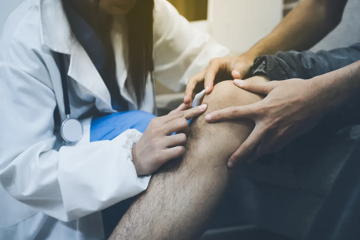 A physician examining a patient's lower leg during a vein screening