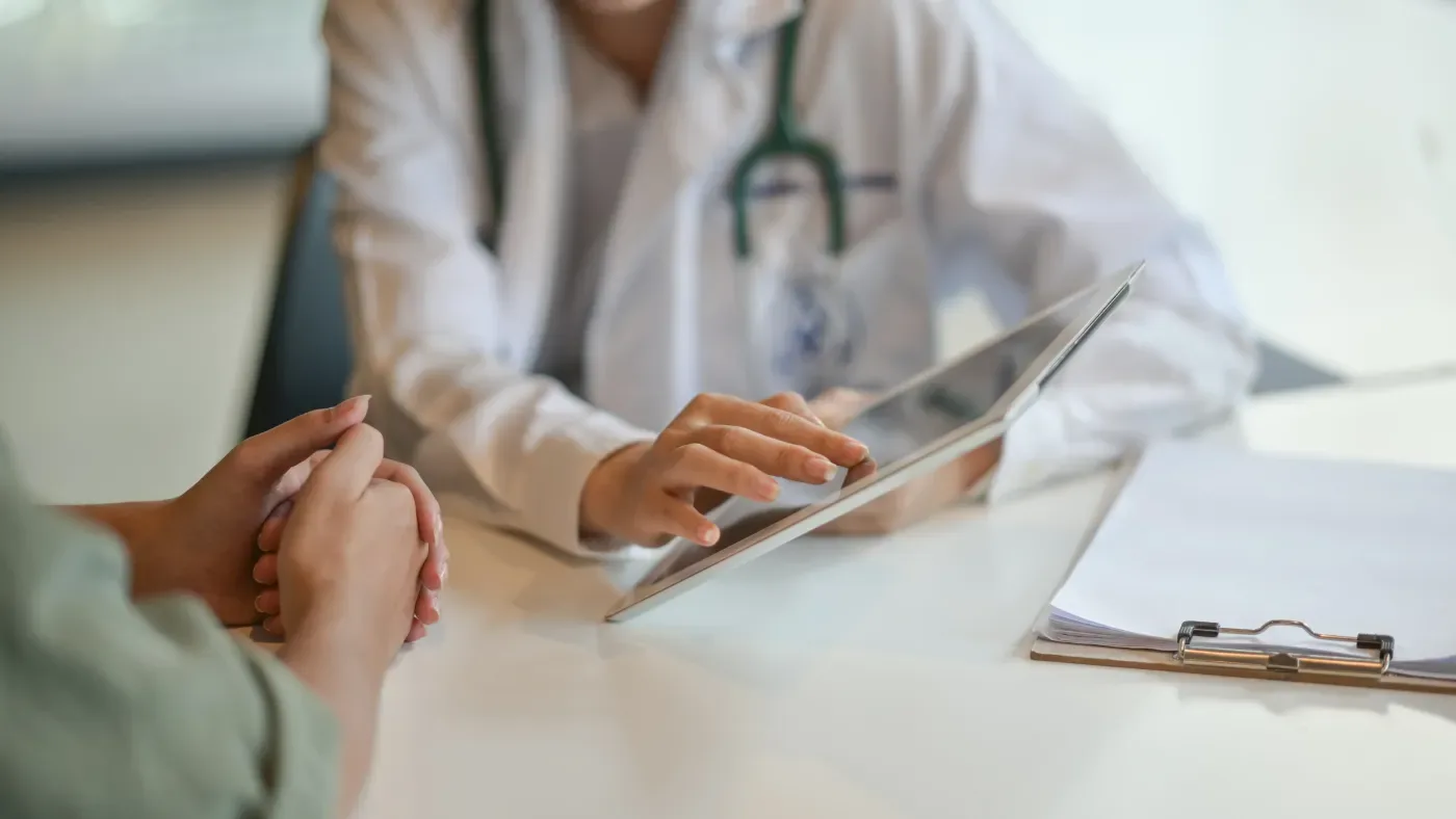 A clinician reviewing findings on a tablet at a consultation desk