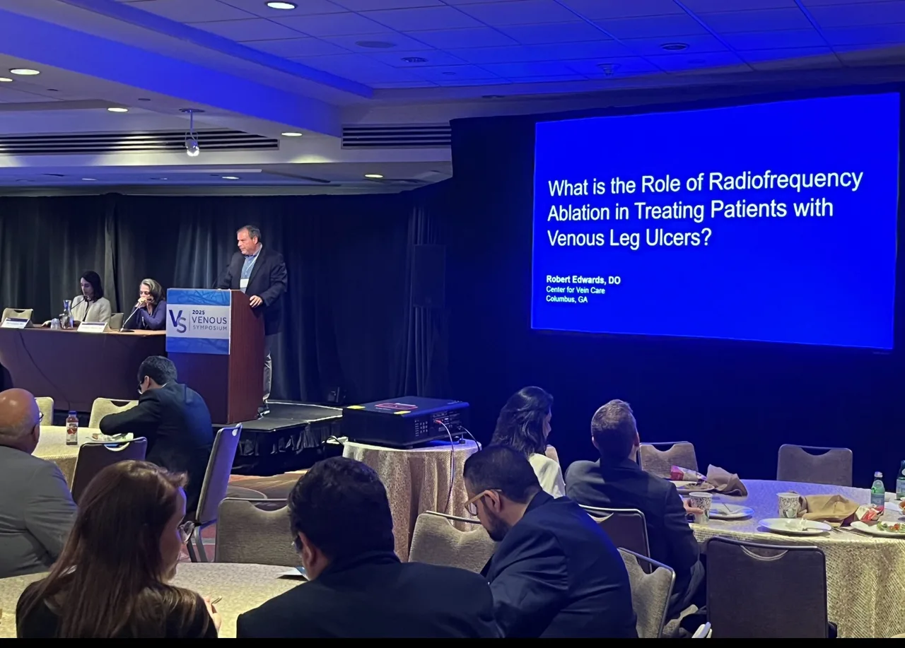 Dr. Robert A. Edwards presenting at the 2025 Venous Symposium in New York City, beside a slide reading “What is the Role of Radiofrequency Ablation in Treating Patients with Venous Leg Ulcers?”